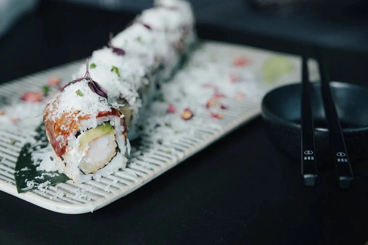 Roll mit Garnelen-Tempura und Avocado auf heller Keramikplatte