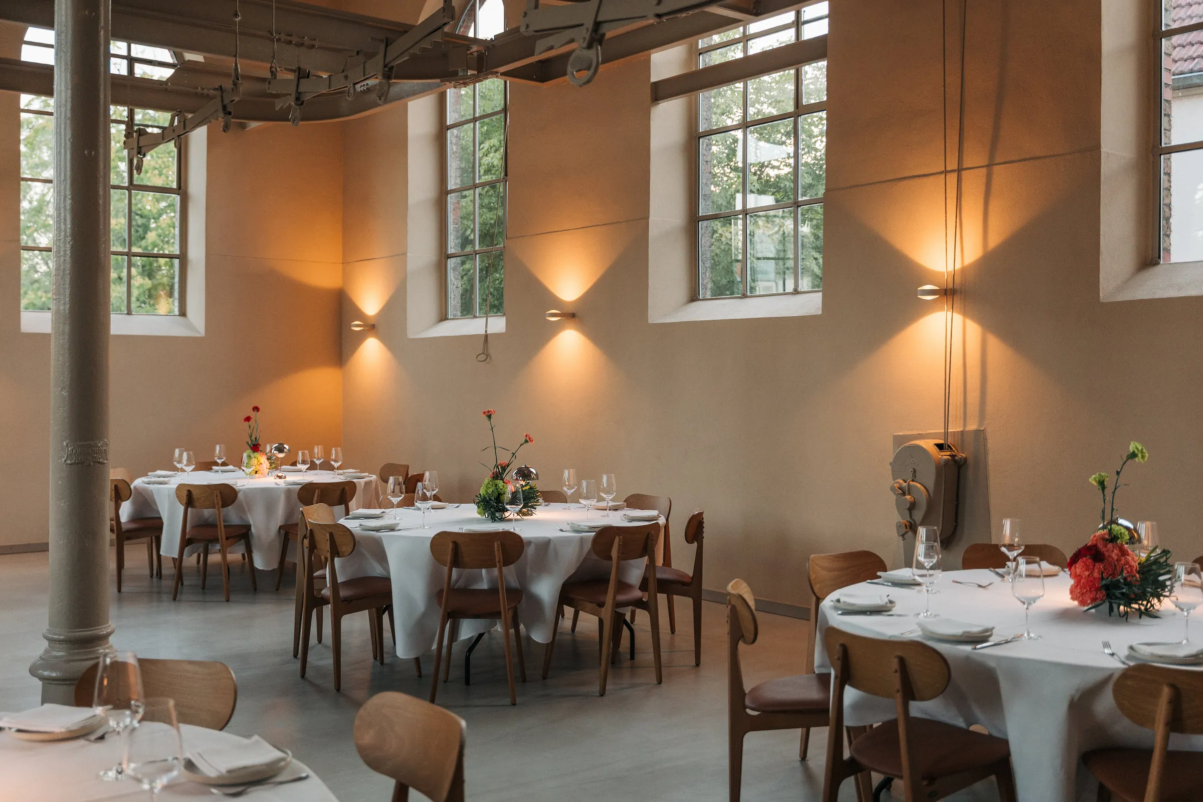 Loft des LAB am frühen Abend mit gedeckten runden Tafeln im Licht der Wandleuchten