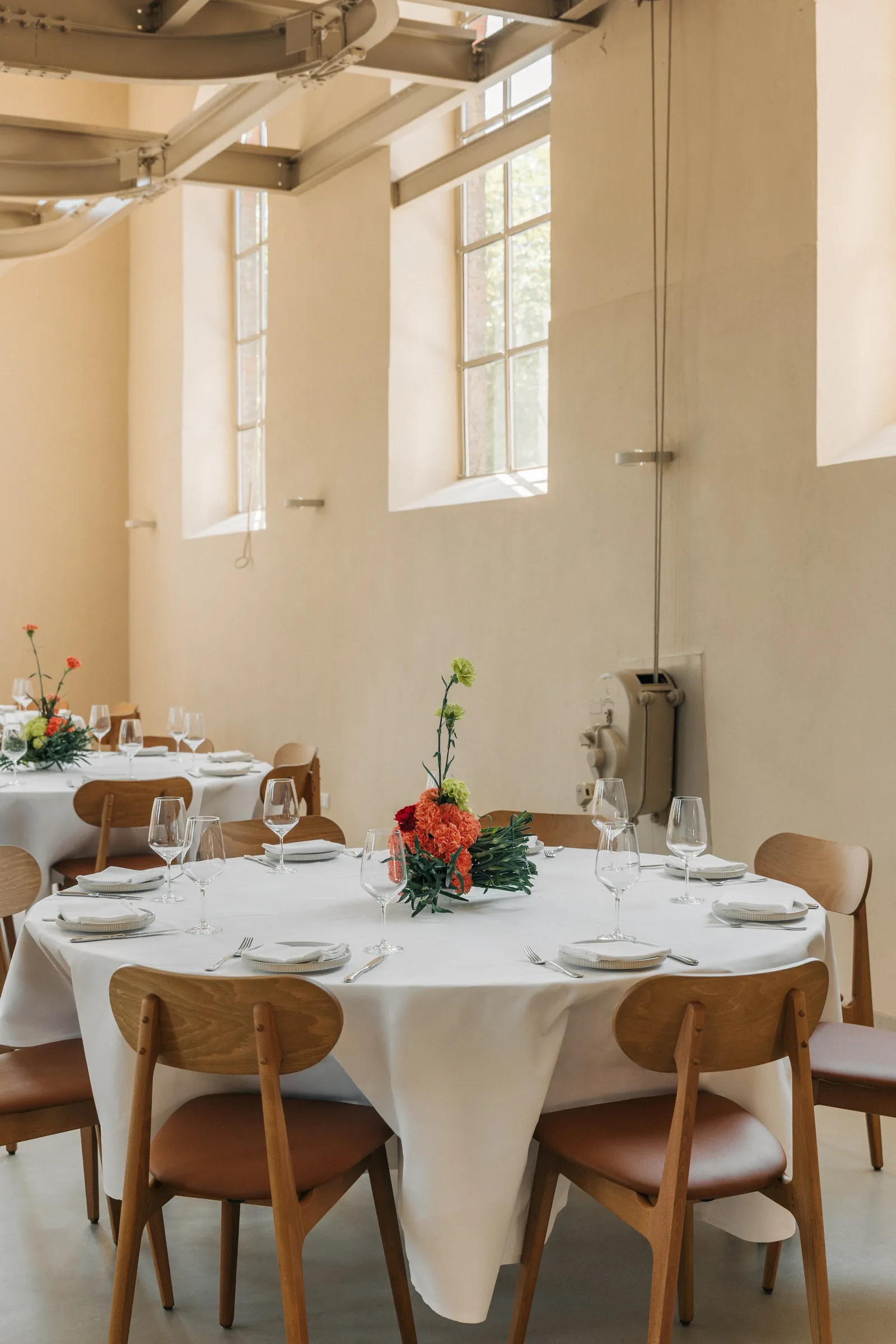 Festlich gedeckte runde Tafel im hellen Loft des LAB unter hohen Sprossenfenstern