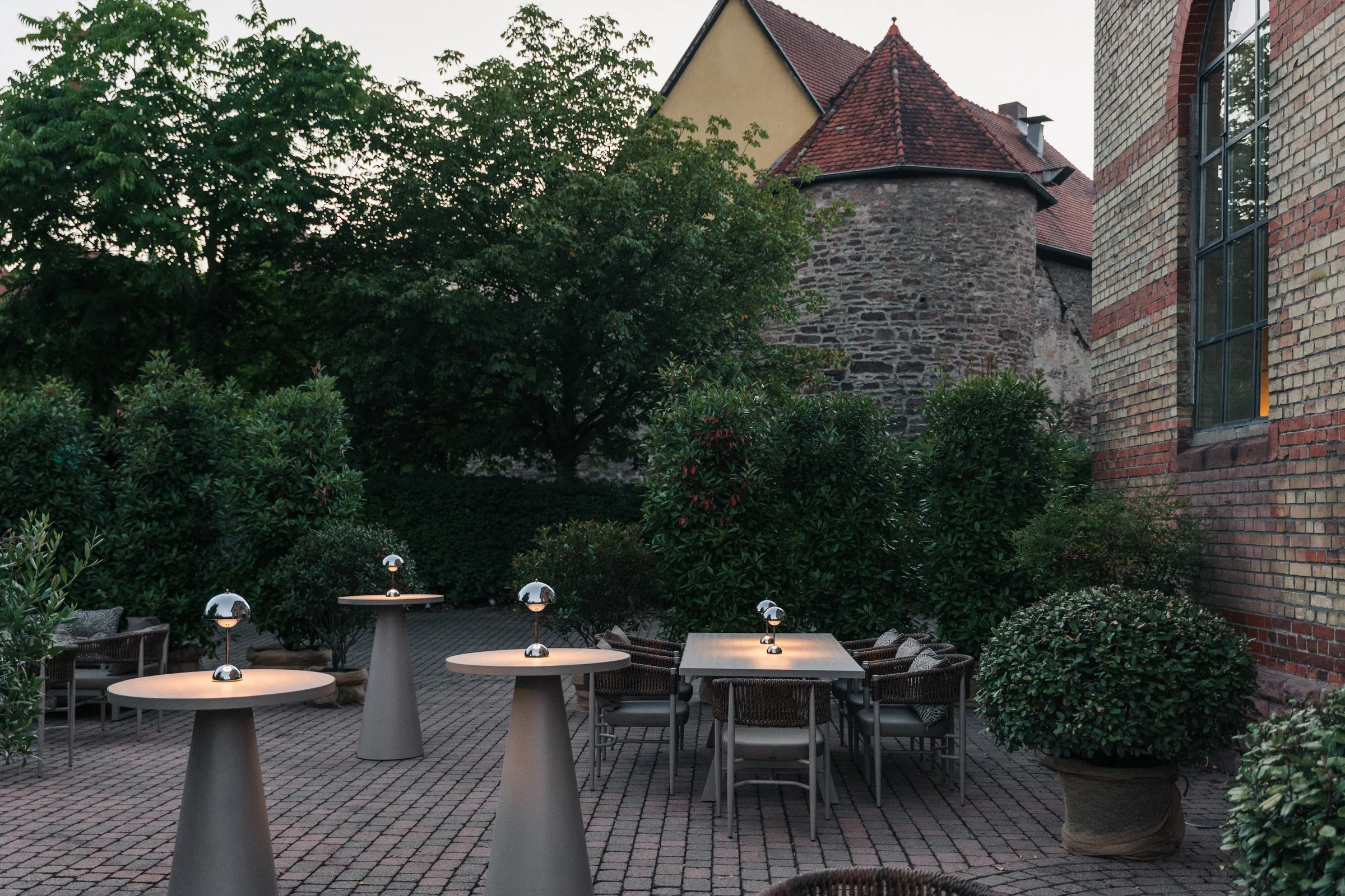 Terrasse des LAB in der Dämmerung mit Stehtischen und leuchtenden Tischlampen