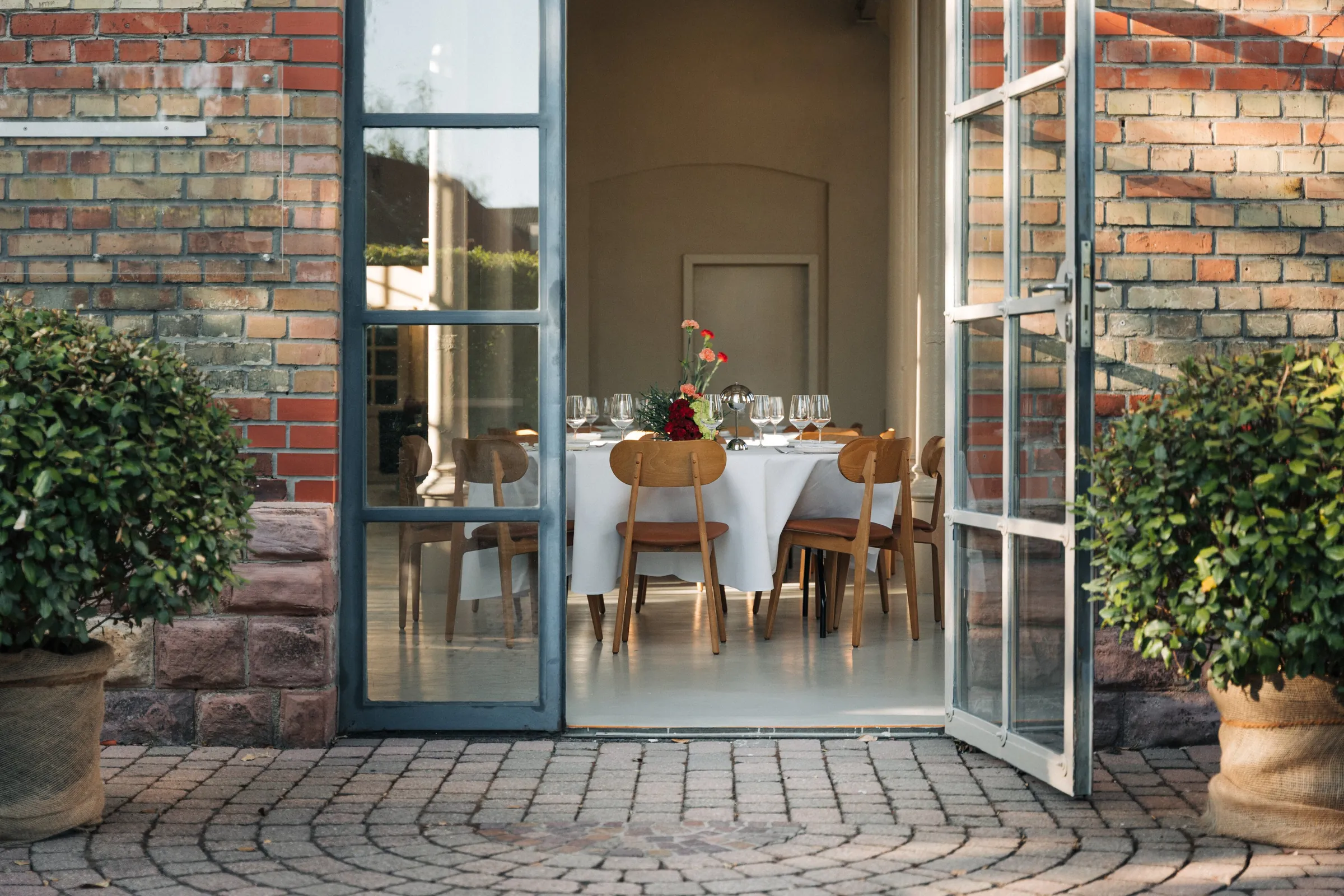 Blick von der Terrasse durch die offene Stahl-Glas-Tür auf eine gedeckte Tafel im Loft