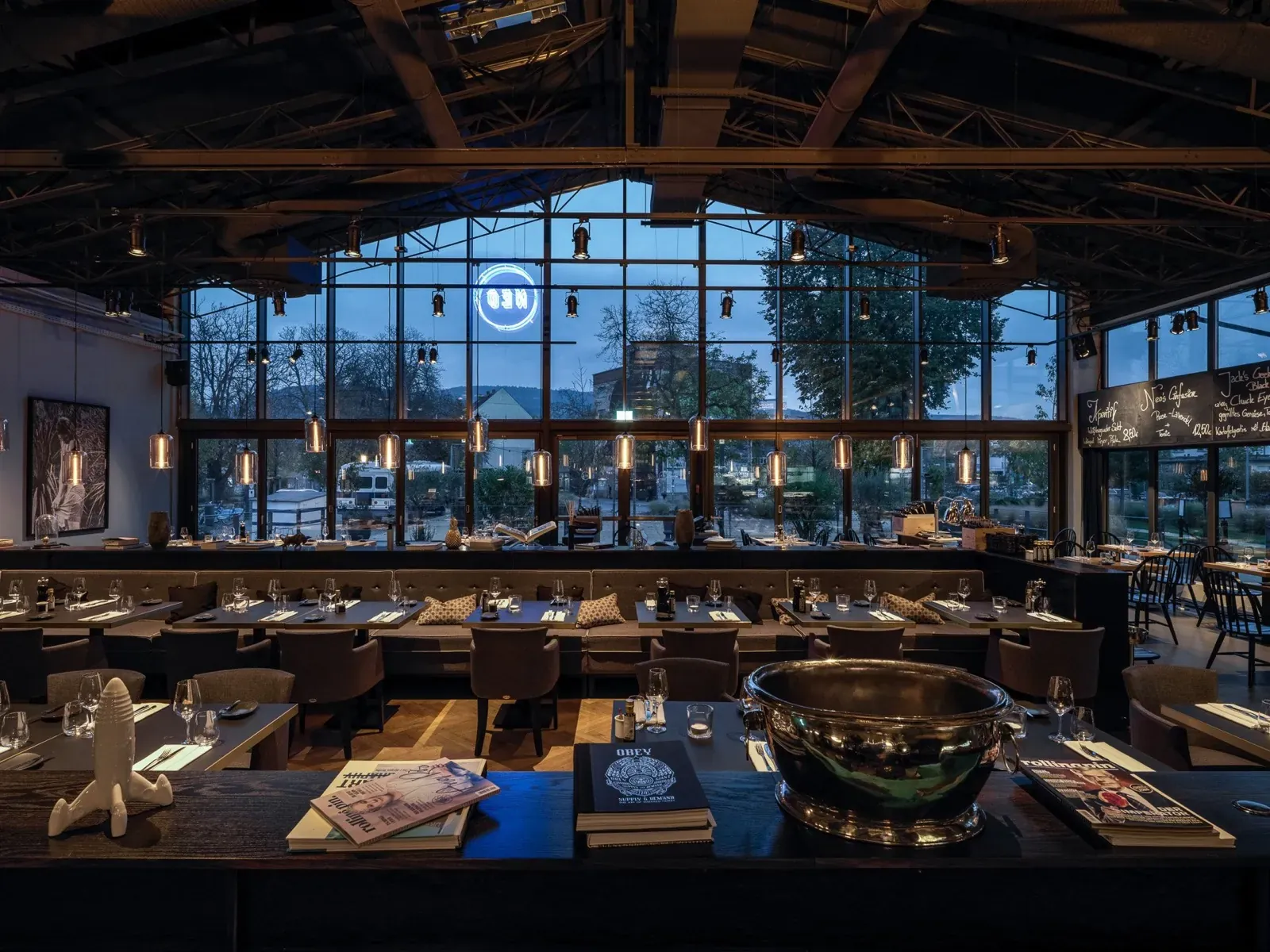 Restaurant-Halle des NEO zur blauen Stunde mit Glasfassade und Neonschild