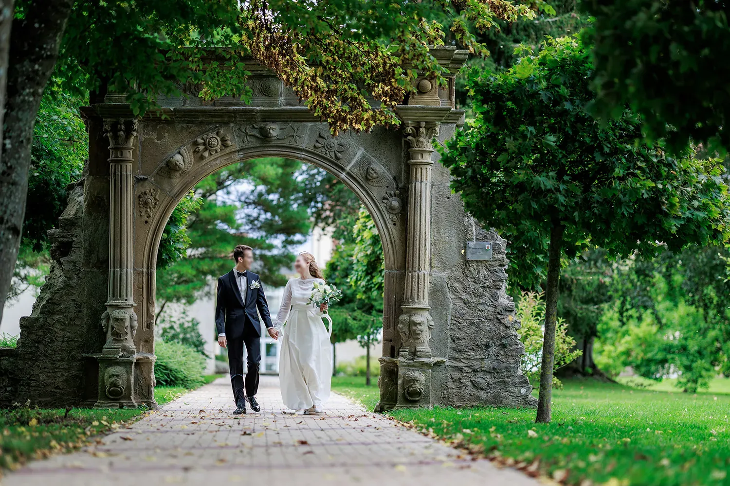 Brautpaar geht Hand in Hand durch das Renaissance-Portal im Schlosspark